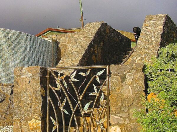 Stone gate with unique metalwork in a rustic setting.