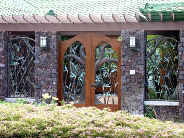 Elegant double wooden doors with decorative glass panels and stone walls.