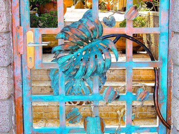 Ornate blue metal gate with a decorative bird sculpture.