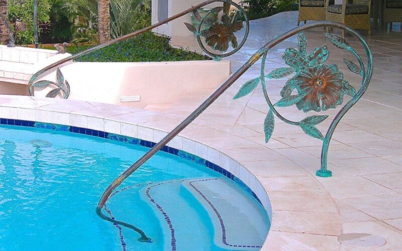 Curved pool steps with decorative metal handrail and tiled edge.