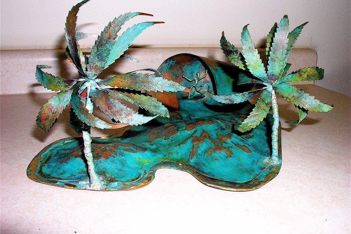 Decorative ceramic piece with two stylized palm trees on a turquoise base.
