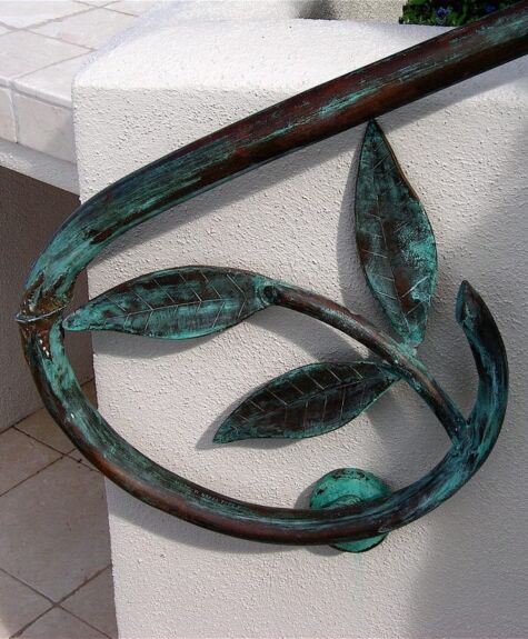 Decorative metal railing with leaf design and green patina.