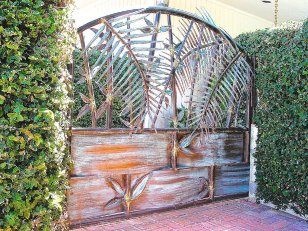 Decorative metal gate with a rustic wooden base set in greenery.