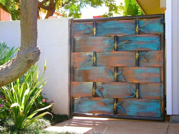 Rustic blue wooden gate with metal hinges under a leafy tree.