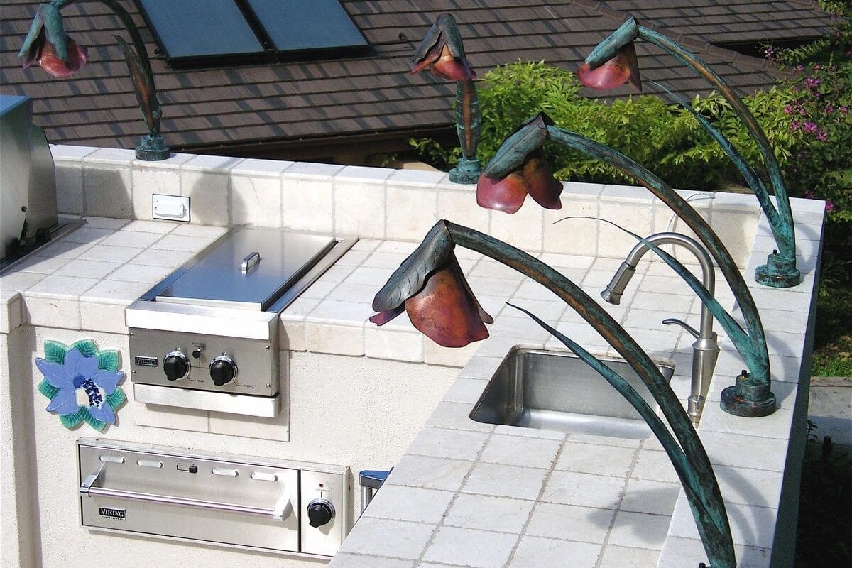 Outdoor kitchen area with built-in grill and unique flower-shaped lights.