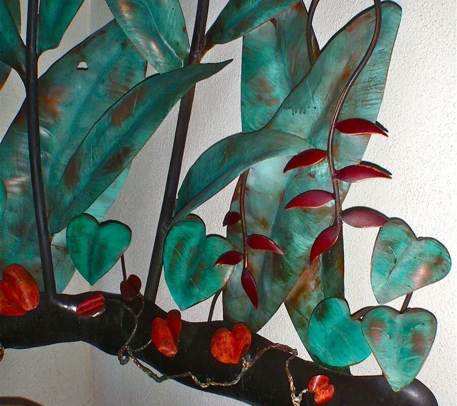 Close-up of a decorative piece with green and red glass elements on black branches.