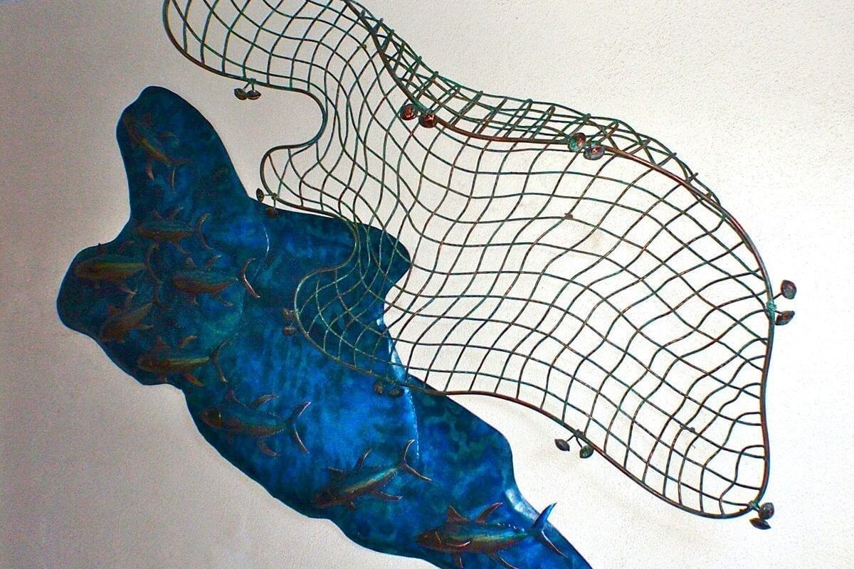 Artistic wall sculpture of a blue dolphin and a net structure.