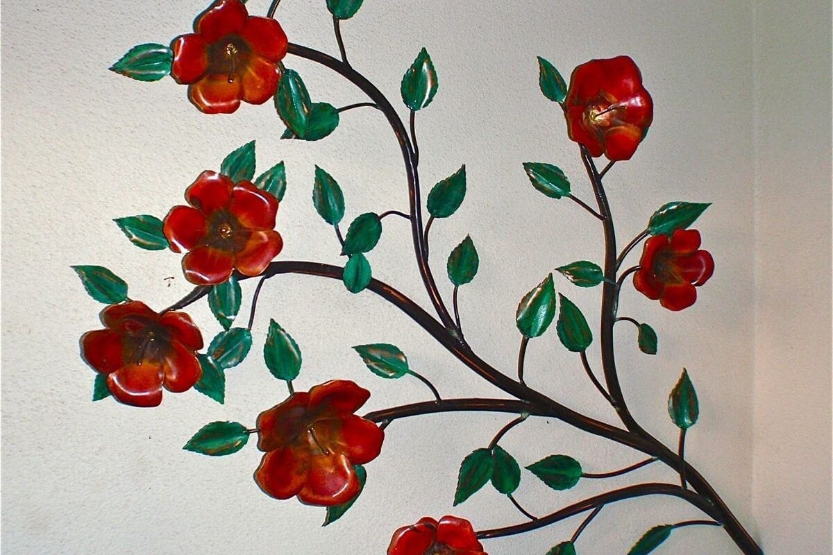Red flowers on dark branches with green leaves against a white background.