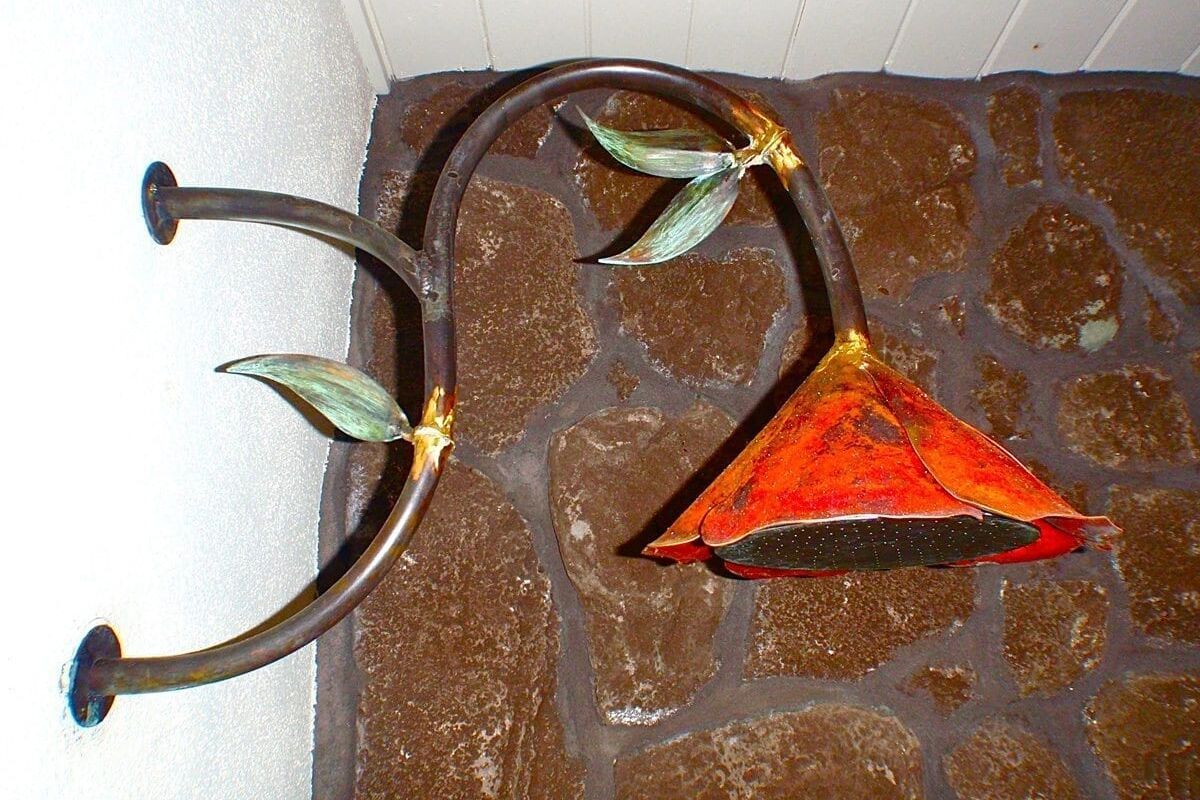 Rustic metal wall hook shaped like a branch with leaves and a red flower.