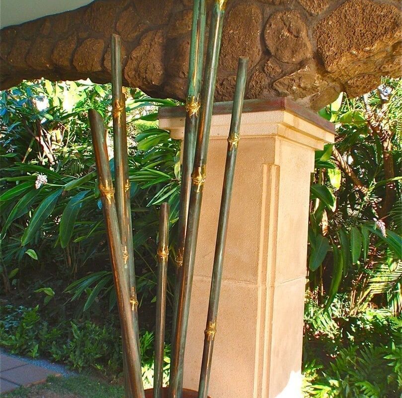 A garden scene with a stone pillar and green bamboo plants.