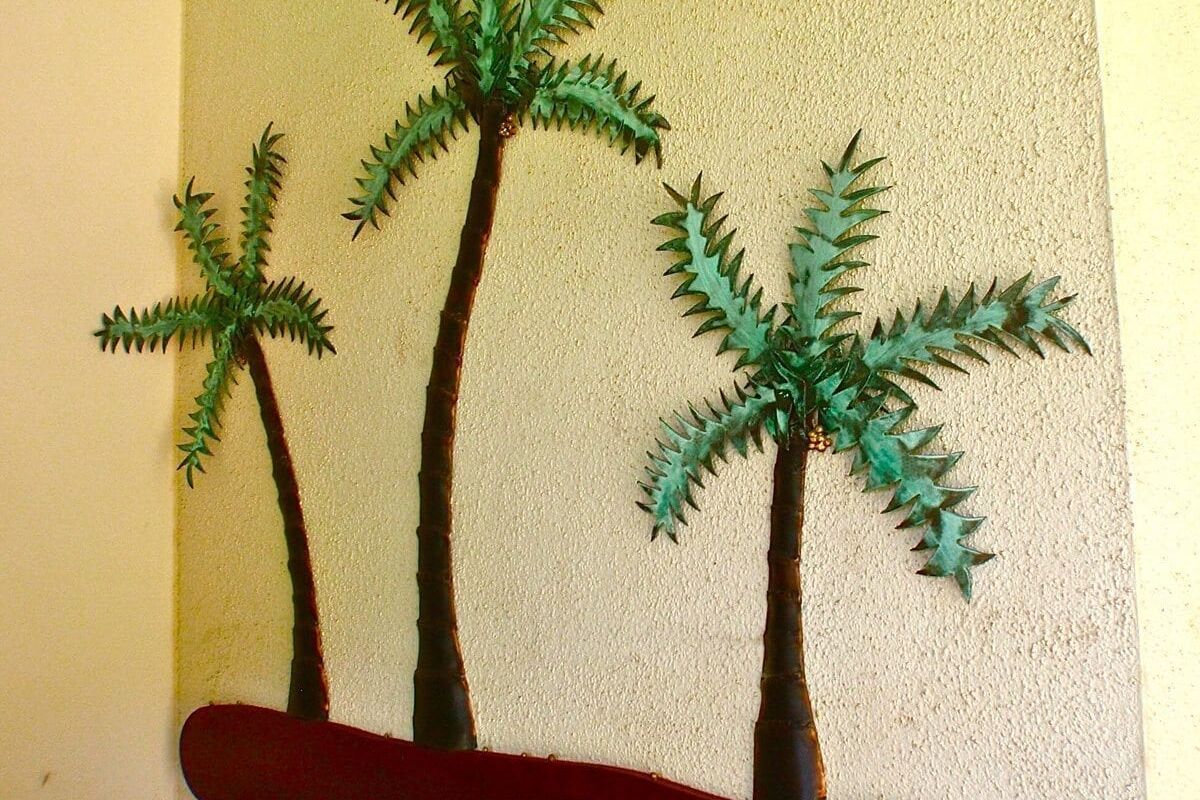 Three palm tree decorations mounted on a wall.