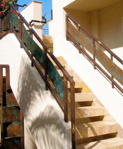 Sunlit outdoor staircase with wooden railings and shadows.