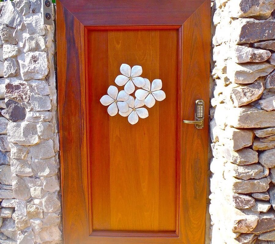 Wooden door with a white floral decoration set in a stone wall.