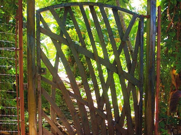 Decorative metal gate with a nature-inspired design in a lush garden.