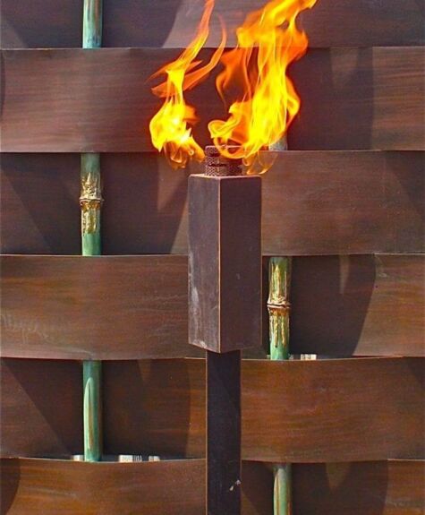 Flaming torch mounted on a wooden frame with metal supports.