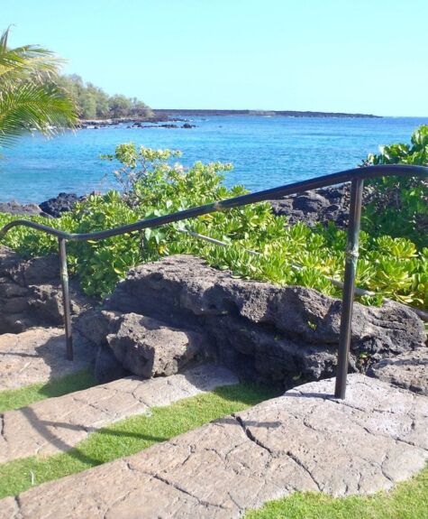 Stone pathway and railing overlooking a scenic ocean view.
