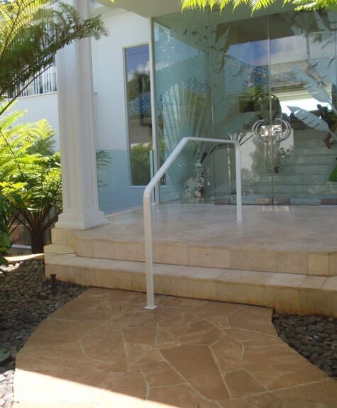 Modern house entrance with glass doors and a handrail.