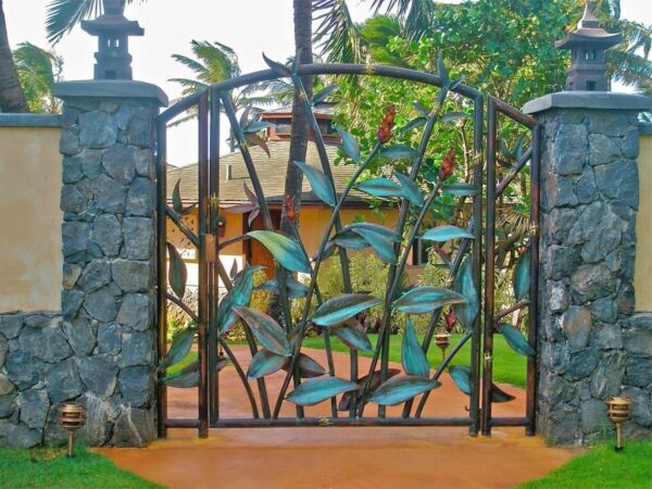 Decorative metal gate with nature-inspired leaf design at a stone entrance.