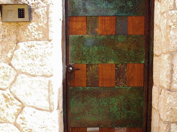 Rustic metal door with a grid pattern set in a stone wall.