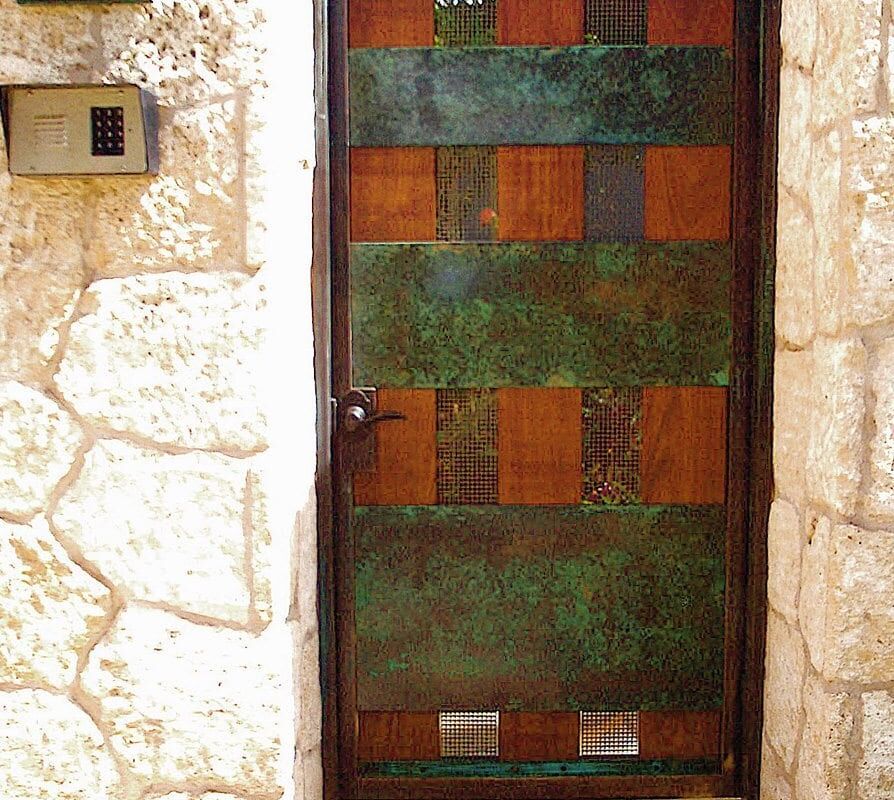 Rustic metal door with a grid pattern set in a stone wall.