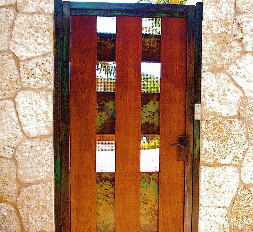A wooden gate with vertical panels set in a stone wall.