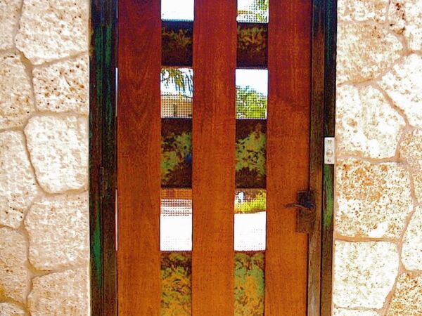 A wooden gate with vertical panels set in a stone wall.