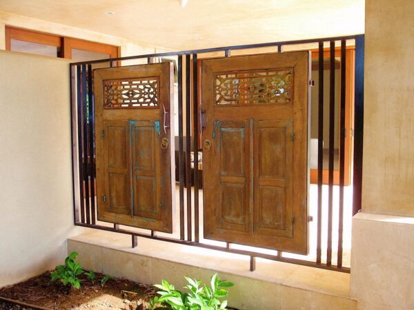 Rustic wooden windows with intricate carvings and metal grills.