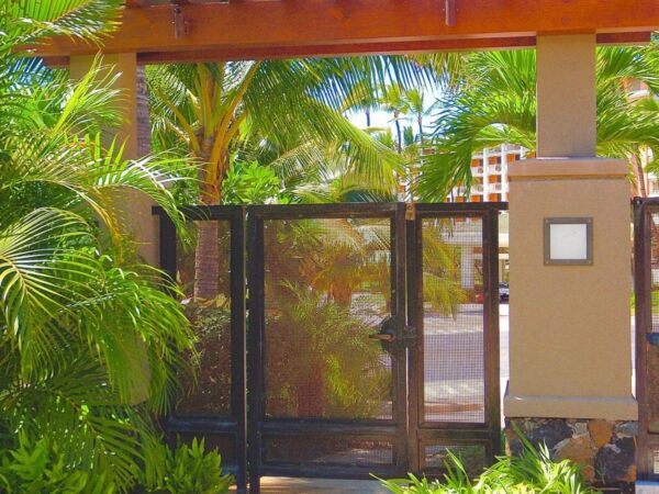 A gated entrance surrounded by lush greenery and a pergola.