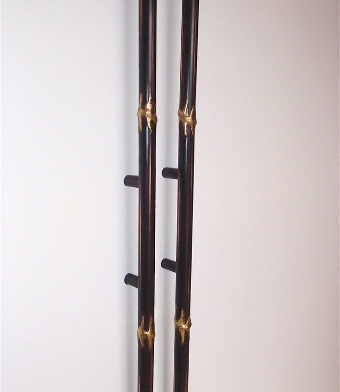 Close-up of black metal poles with gold decorative accents against a light wall.