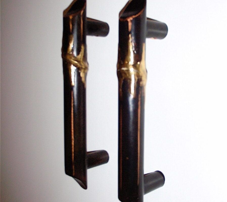 Two black metal handles with gold accents on a white background.