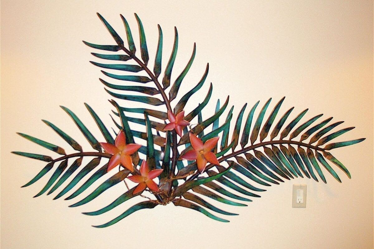 Decorative metal wall art featuring palm leaves and orange flowers.
