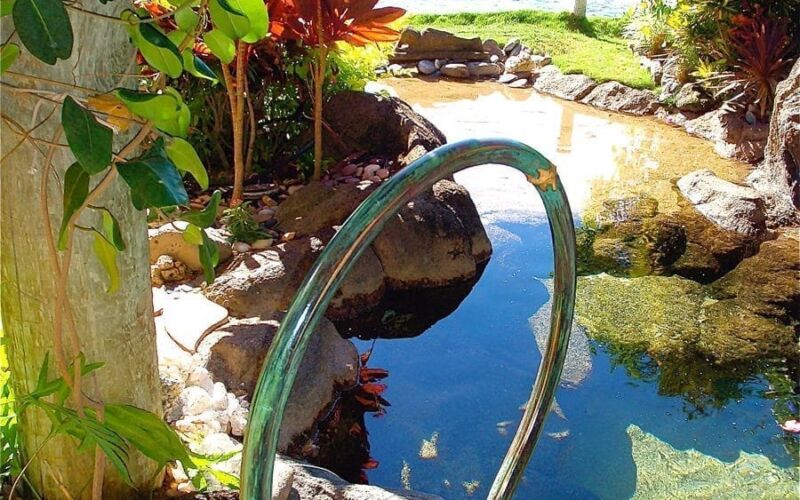 A serene backyard pool with lush greenery and ocean view.