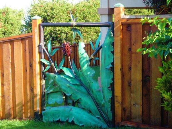 Decorative metal gate with large blue-green leaves and dragonfly design.