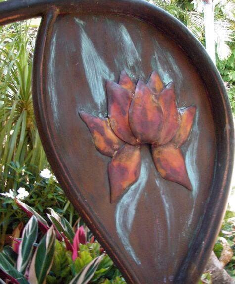 Metal artwork of a flower on a leaf-shaped background.