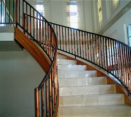 Elegant curved staircase with wooden railing and marble steps.
