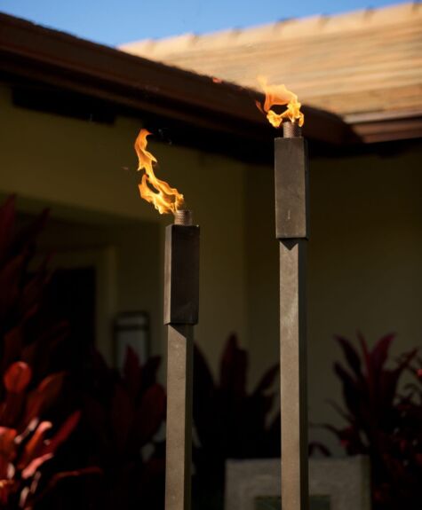 Two tiki torches burning outside at dusk.