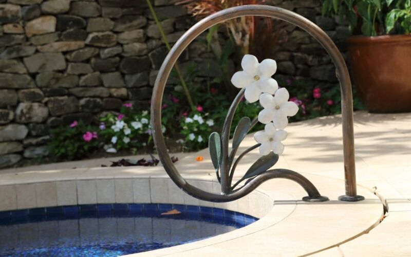 White orchid-shaped pool handrail in a garden setting.
