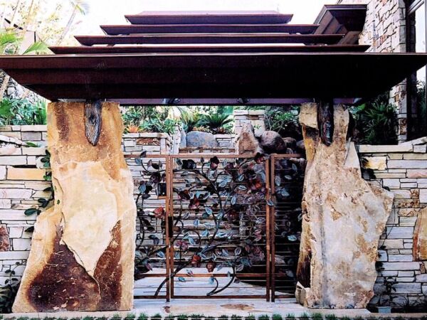 Rustic gate entrance with a metal gate and stone walls.