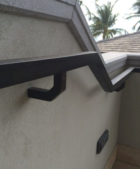 Black metal handrail attached to a gray wall near a corner.