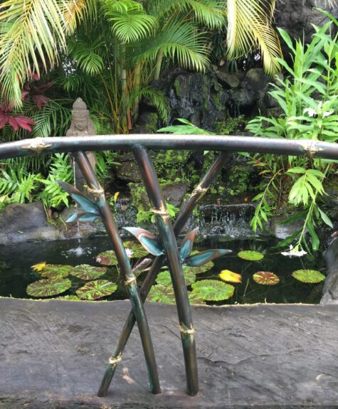 A tranquil garden scene with a bamboo water feature and lily pads.