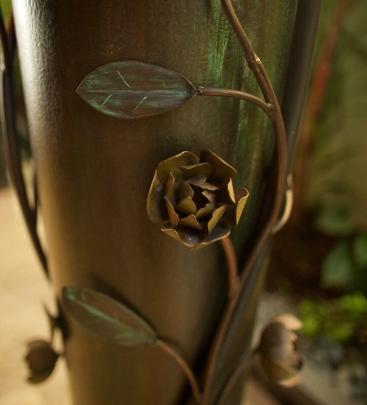 Close-up of a decorative metal flower on a bronze-colored surface.