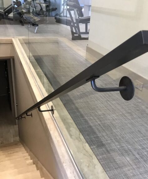 A sleek black handrail along a stairway in a modern building.