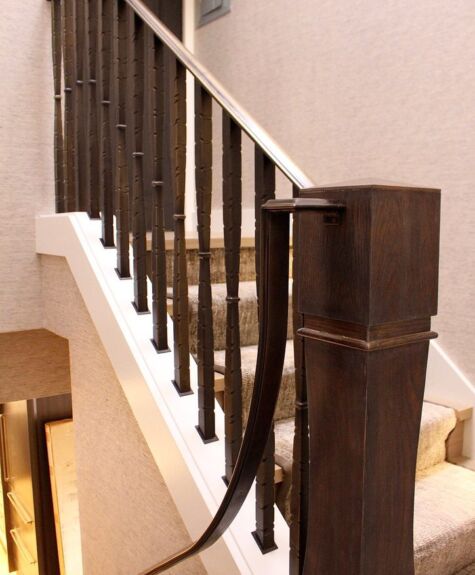 Wooden staircase with dark banister and white base.