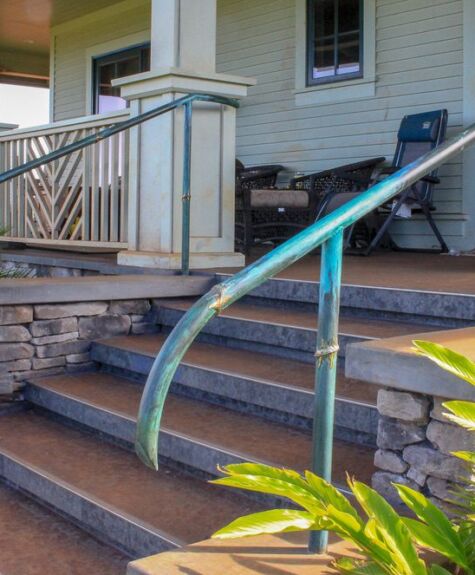 Modern outdoor steps with metal railing and stone siding near a porch.