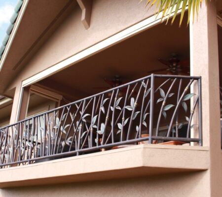 Decorative metal balcony railing with leaf design on a building.