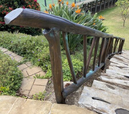 Rustic wooden staircase with a hand-carved railing in a garden.