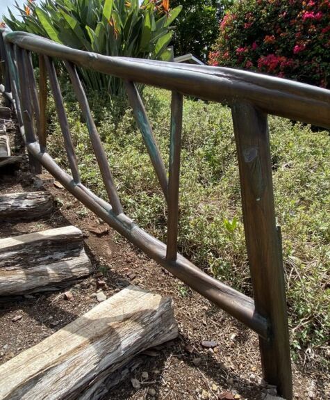 Wooden stairs with a rustic handrail in a garden setting.