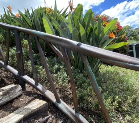 Curved metal railing along garden stairs surrounded by lush greenery.