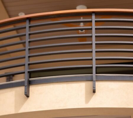 Curved balcony railing with horizontal bars and vertical supports.