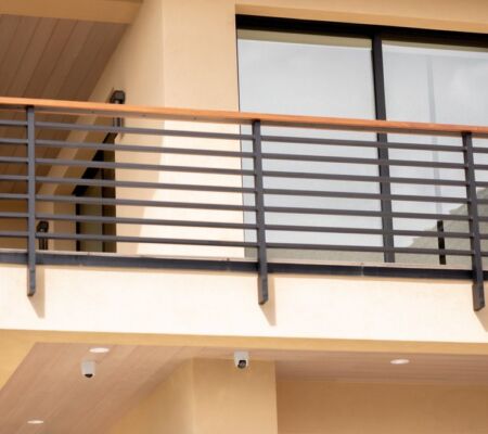 Modern balcony with horizontal metal railing and glass door.